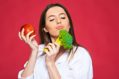 Woman making a kissy face at a head of brocolli in her hand